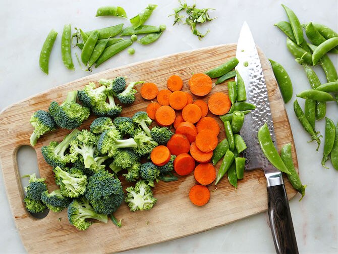 Broccoli, carrots, and peas on a cutting board