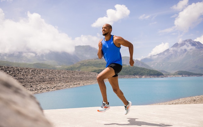 Uomo che corre sullo sfondo di montagne e lago