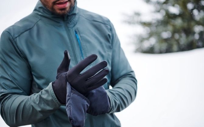 A runner puts on a pair of running gloves before a winter workout.