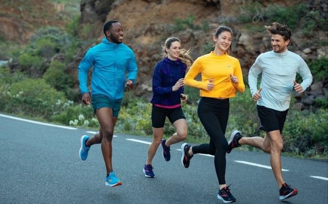 A group of four runners laugh together during a group run.