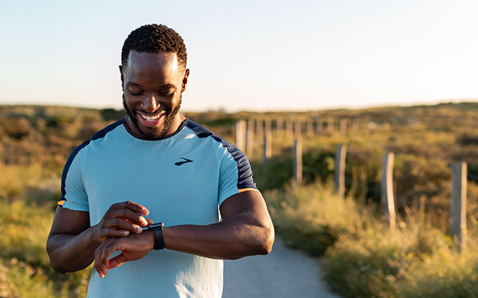 Runner checks their watch on a trail