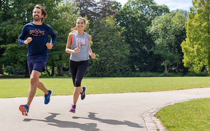 Two runners mid-run on a paved path in a park