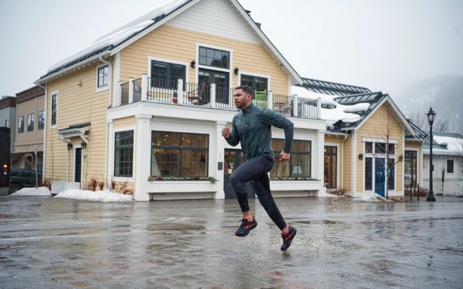Runner in front of large yellow building in the rain