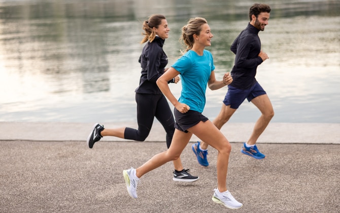Three runners running by a water bay