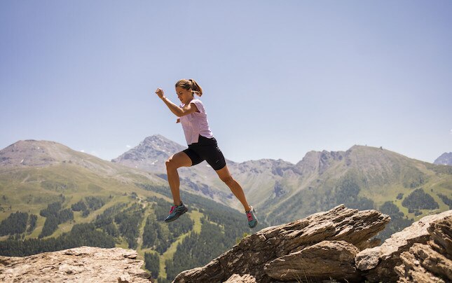 Women jumping from one rock to another on sunny day