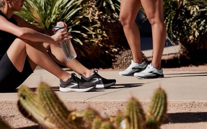 Runner sitting on the pavement drinking water