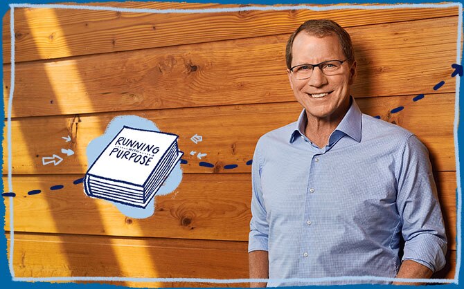 Brooks CEO Jim Weber wearing a light blue dress shirt in front of a wooden wall with illustration of his book entitled Running with Purpose