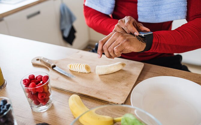 Woman checking watch and having a banana for a snack.