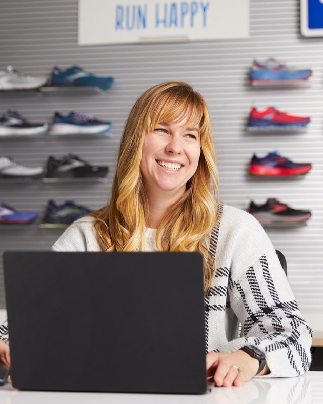 Jen lächelt in die Kamera und sitzt am Computer