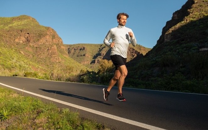 A runner on a paved road in the early morning.