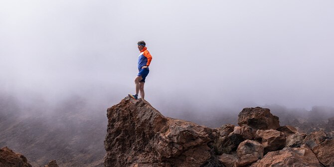 Scott Jurek de pie sobre una roca durante una carrera de trail.