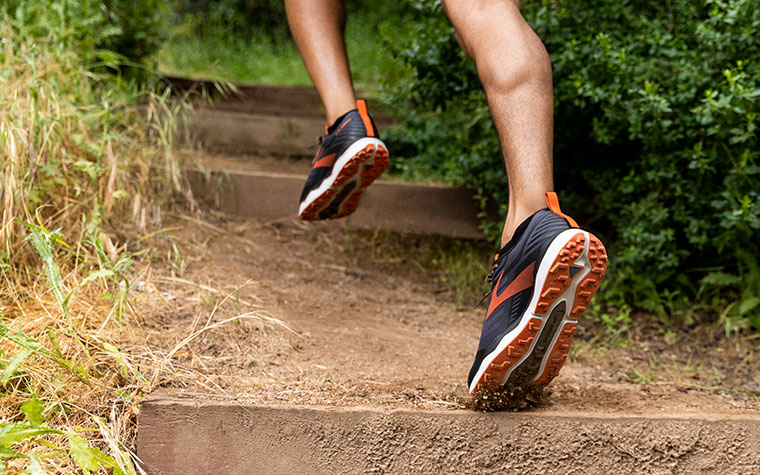 Close-up of runner’s feet in the Caldera, ascending stairs on a dirt trail.