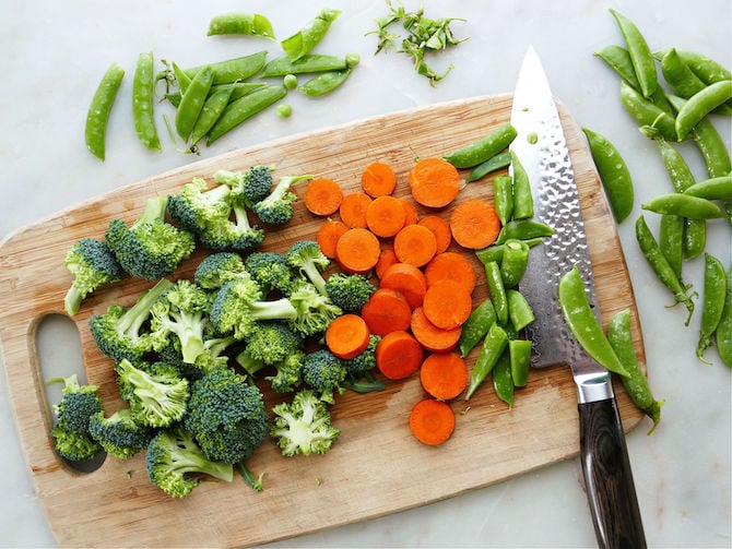 Broccoli, carrots, and peas on a cutting board