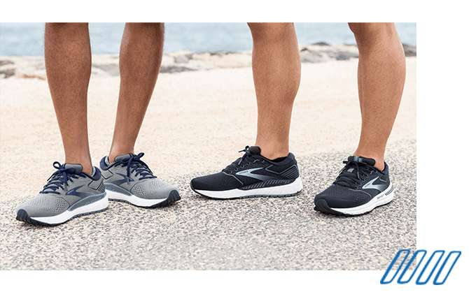 Nahaufnahme der Beine von zwei Läufern, die Brooks Beast-Schuhe mit GuideRails-Technologie tragen.