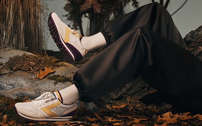 Close up of someone wearing the Brooks Chariot shoes while laying on leaves and rocks