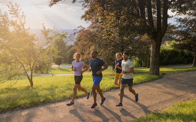 A group of four runners on a morning jog through a park.