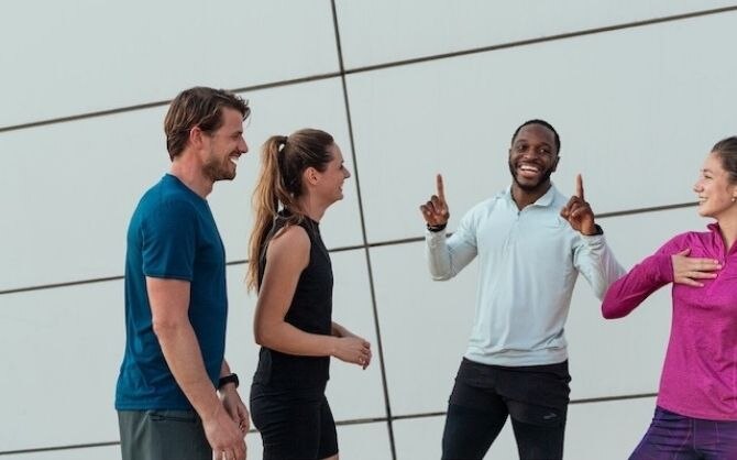 A group of four runners laugh together after a group run.