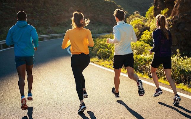 Four people running on a sunny street
