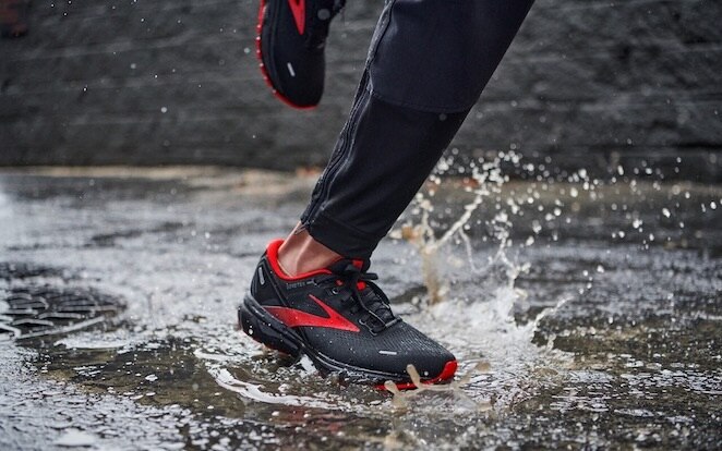 Un runner compie un passo in una pozzanghera d’acqua mentre corre sotto la pioggia