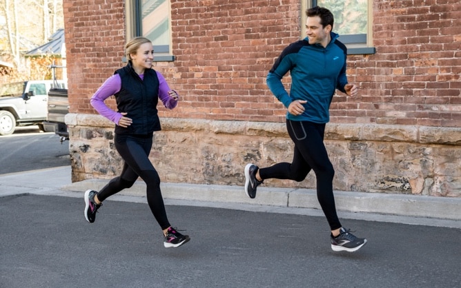 Two runners with a brick wall behind them
