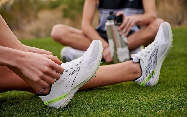 A runner sits down to drink water after a run.