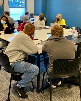 A group of BoMF members and volunteers work through job skills training.