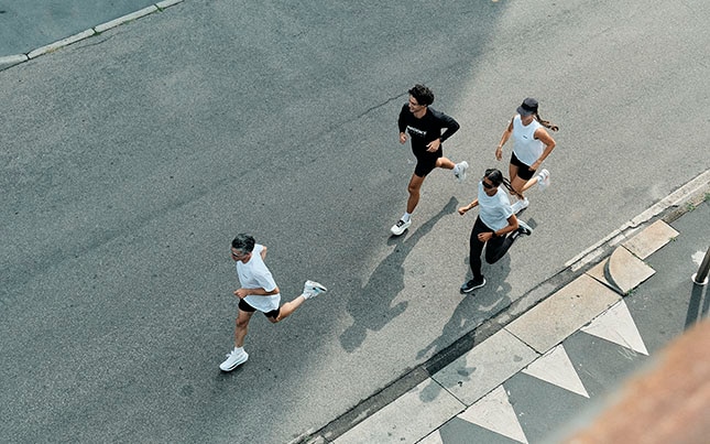 Overhead shot of four people running on pavement in Brooks