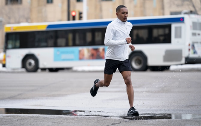 A runner steps in a puddle of water while running in the rain.