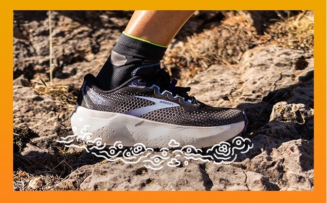 Close-up of a foot wearing a Brooks trail running shoe surrounded by bubbles