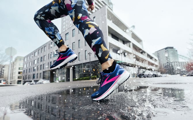 runner runs through a puddle in the rain