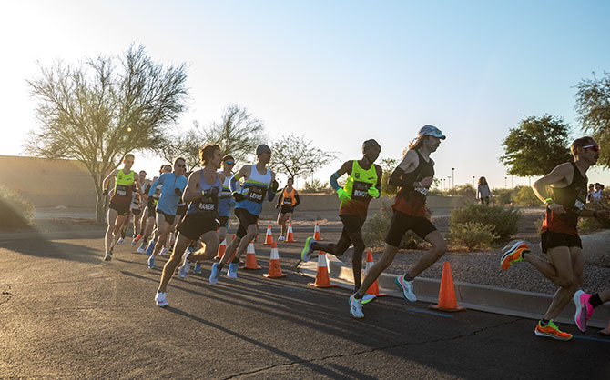 Un groupe de coureurs et coureuses aborde un virage sur le parcours. 