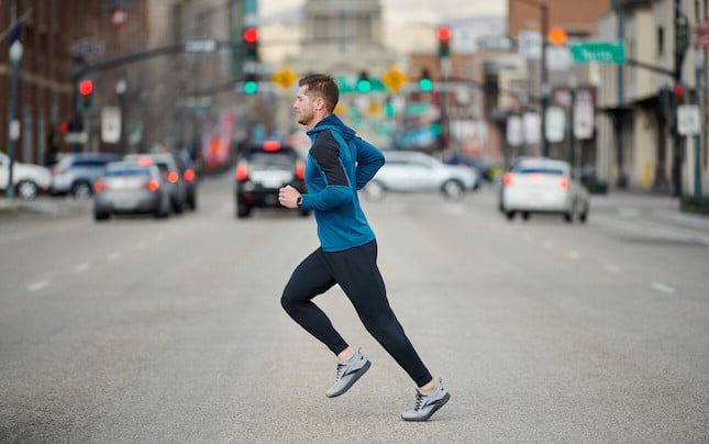 Side view of a runner crossing a busy city street