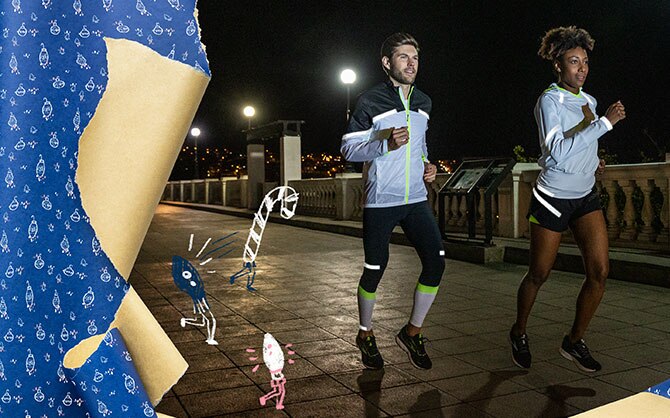Un homme et une femme portant des vêtements réfléchissants Brooks Run Visible courent le soir.