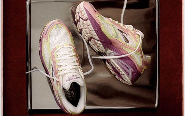 Close up of the Brooks Adrenaline GTS 4 shoes laid on a metal table and a maroon background