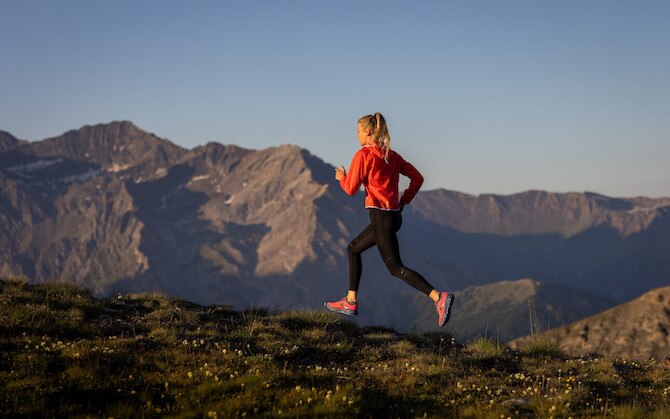 A runner jogs along a mountain ridge during a trail running race.