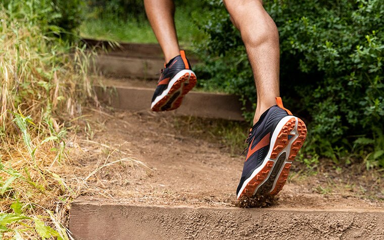 Close-up of runner’s feet in the Caldera, ascending stairs on a dirt trail.	