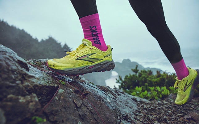gros plan des pieds d’une personne qui pratique la course en sentier dans les chaussures de course en sentier Brooks Cascadia 19