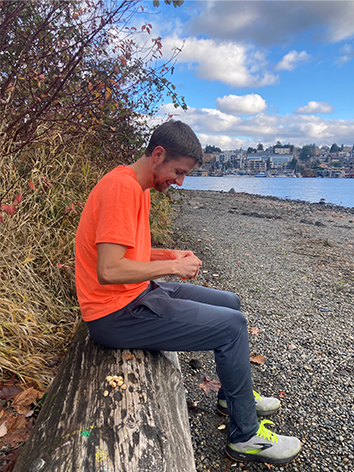 Joe sitting on a log by the water