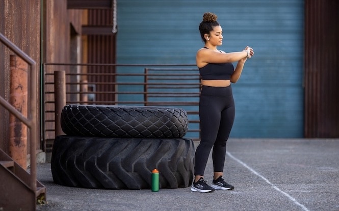 A runner prepares for a cross-training workout while looking at their watch.