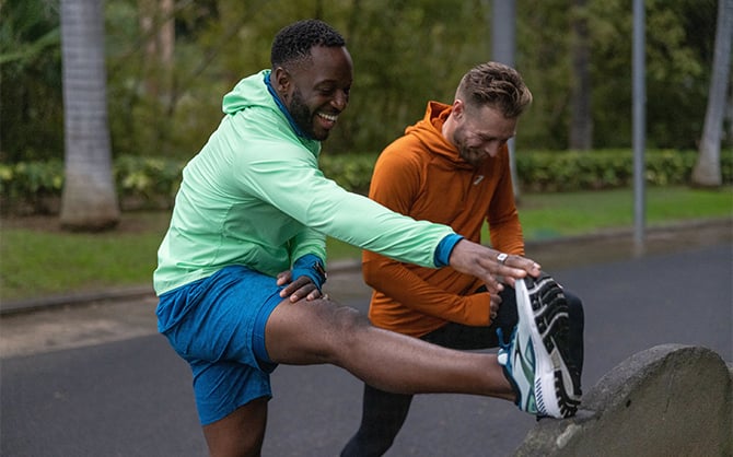 Medium shot of two men wearing Brooks stretching