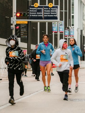 Andrea Guerra and Grace Zamudio run the We Are Houston 5K with youth athletes.