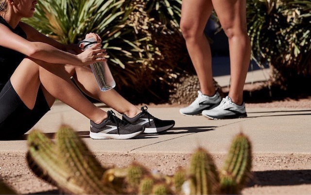 A runner sits down to drink water after a run.