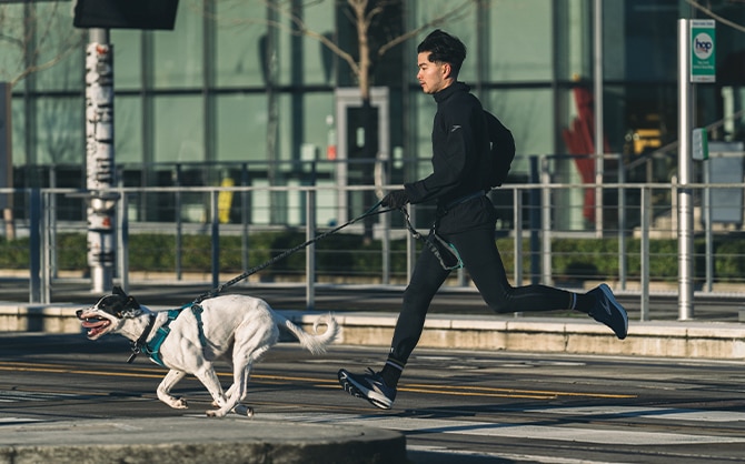 Un homme et son chien sprintent de l’autre côté d’une rue.