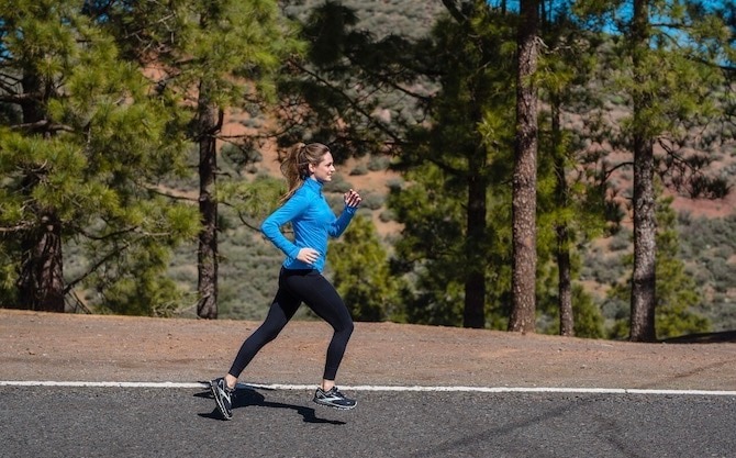 woman running on the road next to trees