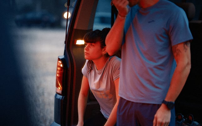 Rückansicht von zwei Läufer*innen auf einem Sandweg mit Blick auf eine Stadt.