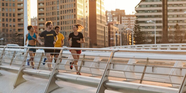Eine Gruppe von Läufern laufen über eine Brücke bei Sonnenaufgang.
