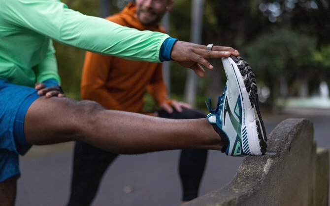 Een hardloper die zijn hamstring strekt na het hardlopen