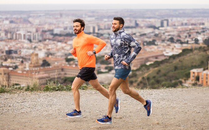 Two runners striding forward on a hilly track