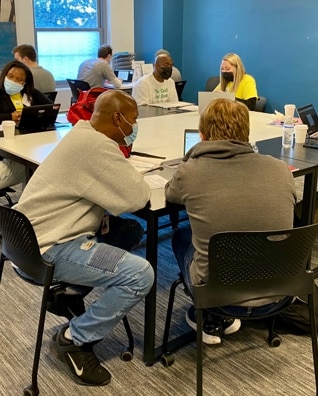 A group of BoMF members and volunteers work through job skills training.