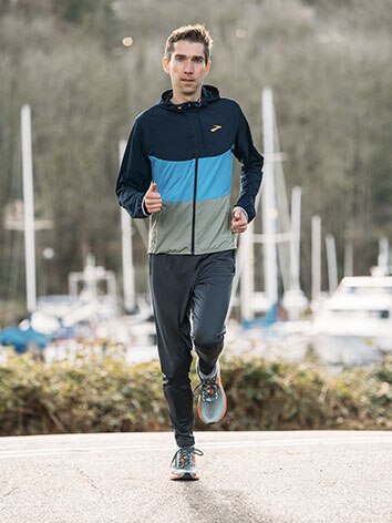 Runner courant en portant la veste Canopy et des chaussures Brooks